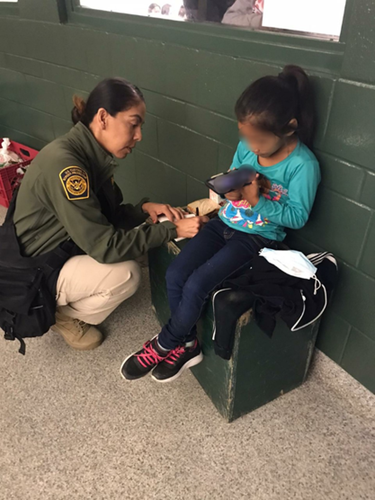 Border Patrol agent kneels next to child