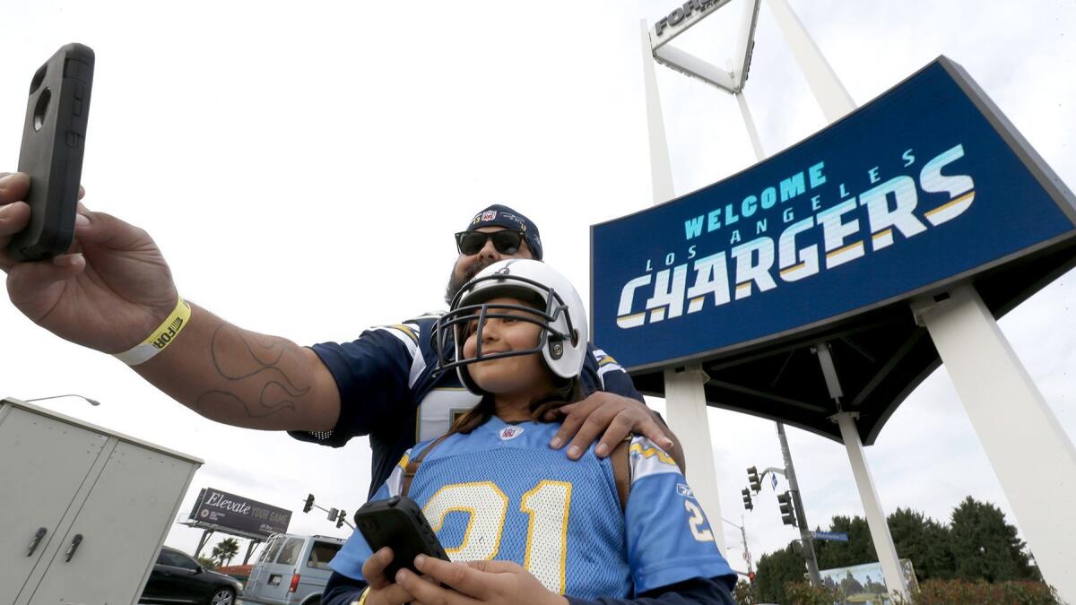 Chargers fans Luis Salas and his daughter Lily Salas, 9, take a photo together in front of a "welcome Los Angeles Chargers" sign at the Forum following a ceremony to kick off Chargers football coming to Los Angeles.