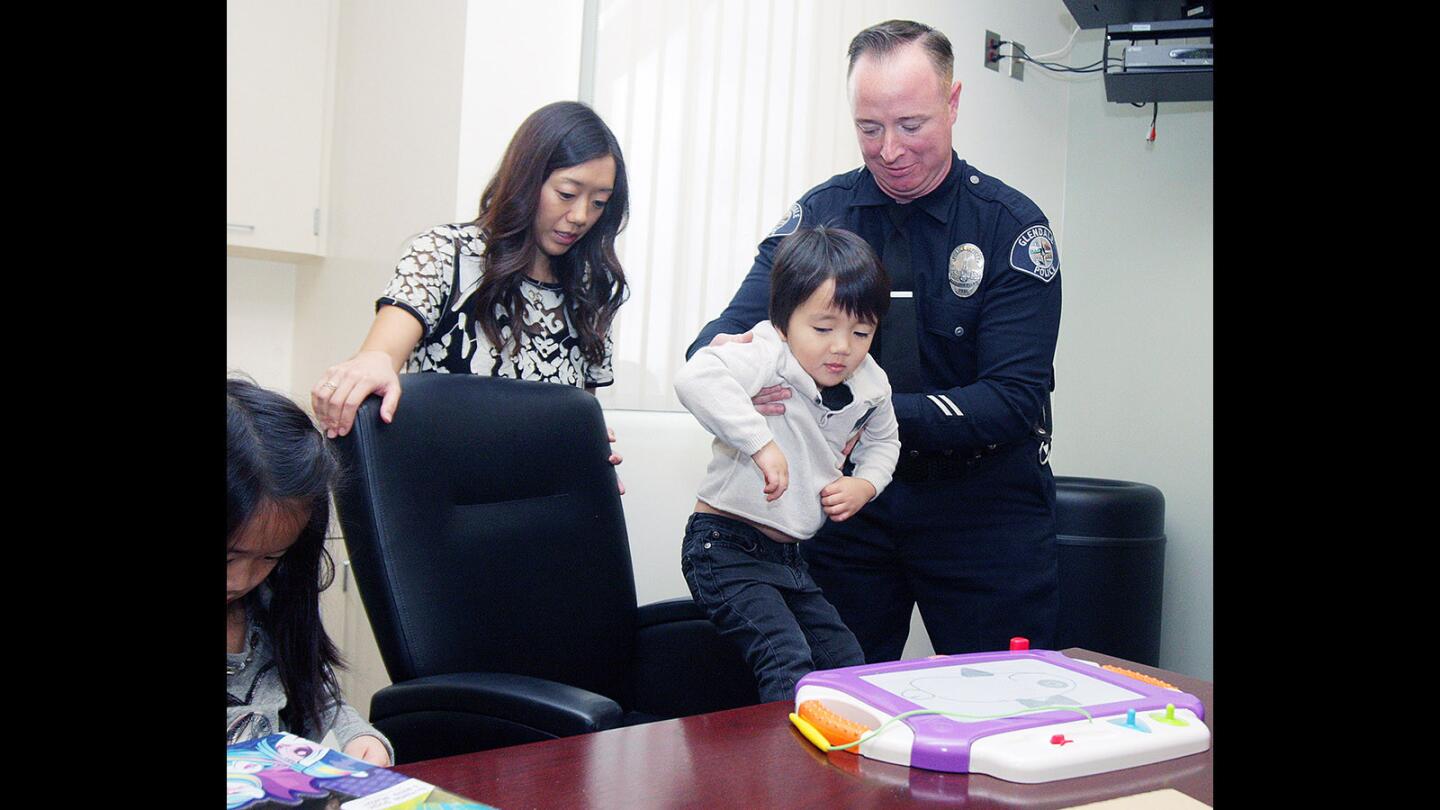 Clayton Cha, 3, of Glendale, is lowered into his chair by Glendale Police Officer James Colvin under the watchful eye of Clayton's mother Jennifer. Last April, Colvin was the first on the scene to treat then 2-year-old Clayton, who had fallen on his head from 22-feet onto concrete.