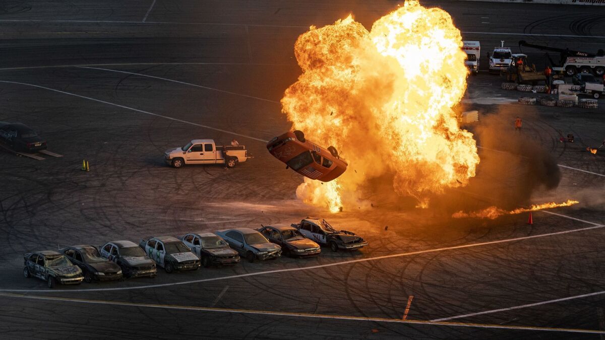 A stunt driver successfully spins a Ford over eight cars in one of the night's early jumps. The flames were set intentionally to enhance the spectacle.