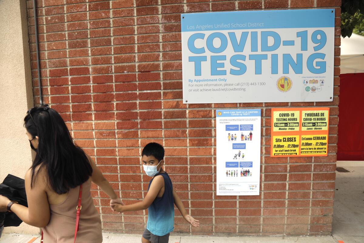 A parent and child walk to a COVID-19 testing site.