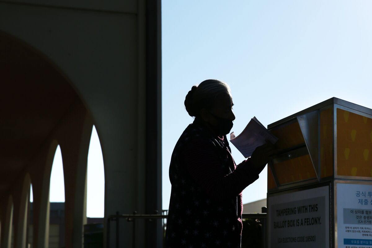 A voter drops a ballot into a box.