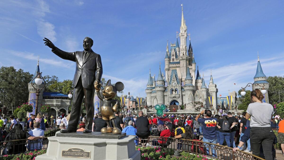 Guests watch a show near a statue of Walt Disney and Micky Mouse at Walt Disney World in Lake Buena Vista, Fla. Walt Disney Co. reported second-quarter earnings Wednesday.