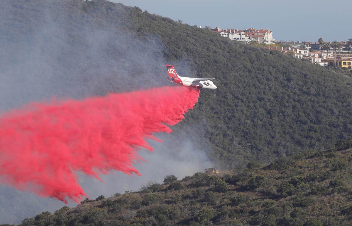 A firefighting aircraft drops fire retardant on a hillside in Aliso Canyon on May 11.