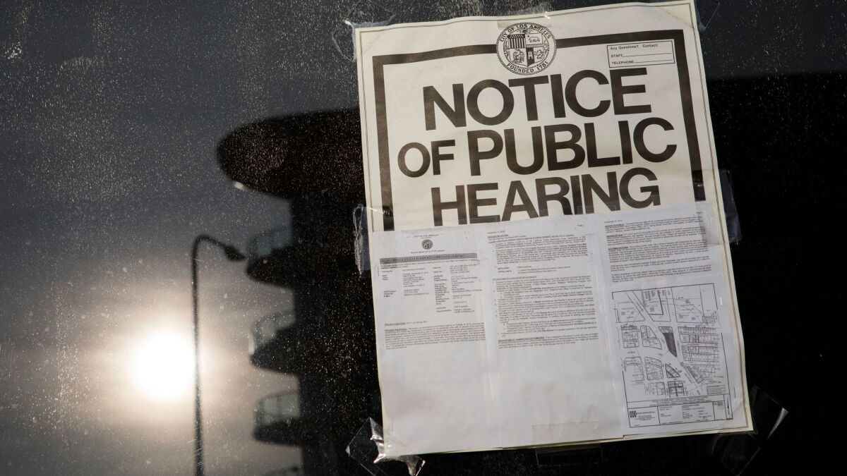 A Notice of Public Hearing displayed on the window of a proposed development site at the intersection of San Vicente and La Cienega on December 14, 2016.