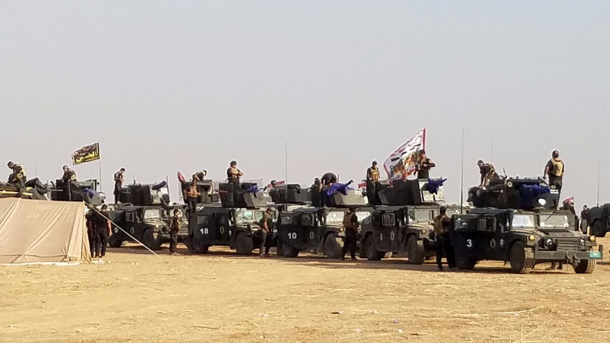 Iraqi army troops fly a sectarian Shiite flag as they gather in Tel Aswad, Iraq.