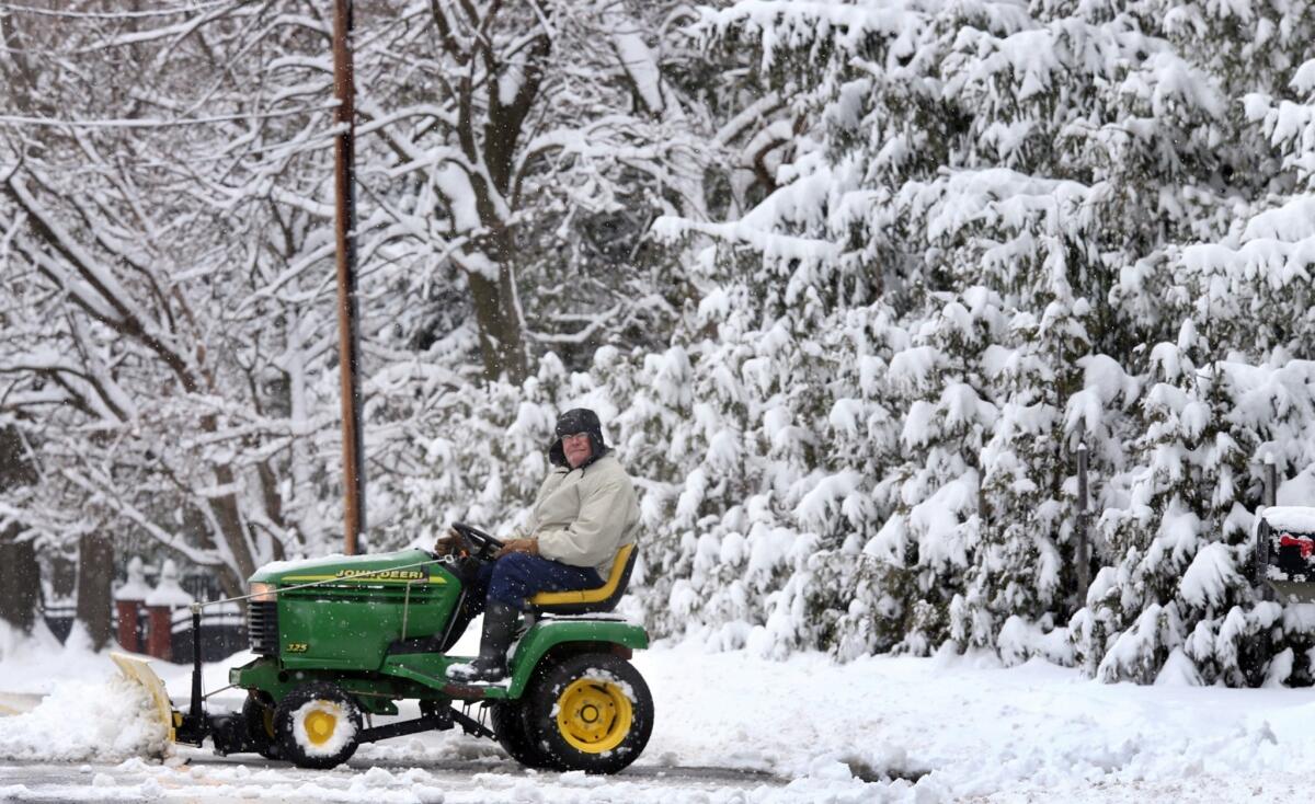 Peter McAuley uses his lawn tractor to clear snow from his driveway in Winchester, Va. Despite the harsh winter, business economists expect economic growth to improve this year.