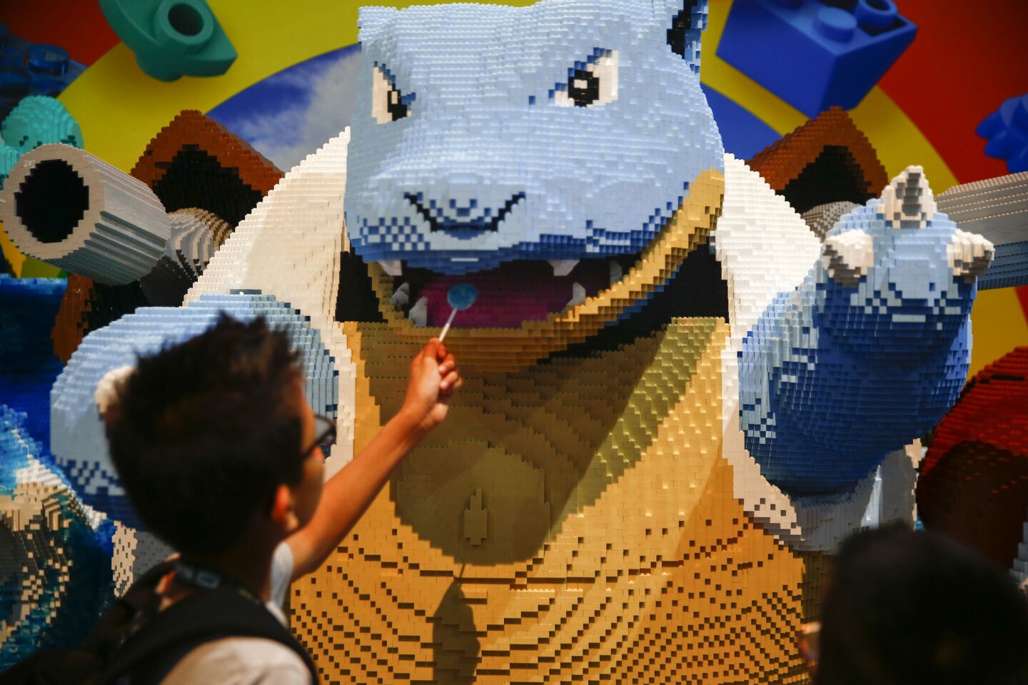 Tyler Lokum, 8, of Los Angeles offers his lollipop to a Mega Construx of the Pokemon Blastoise at the Mega Construx booth during a preview of the 2018 San Diego Comic-Con International.