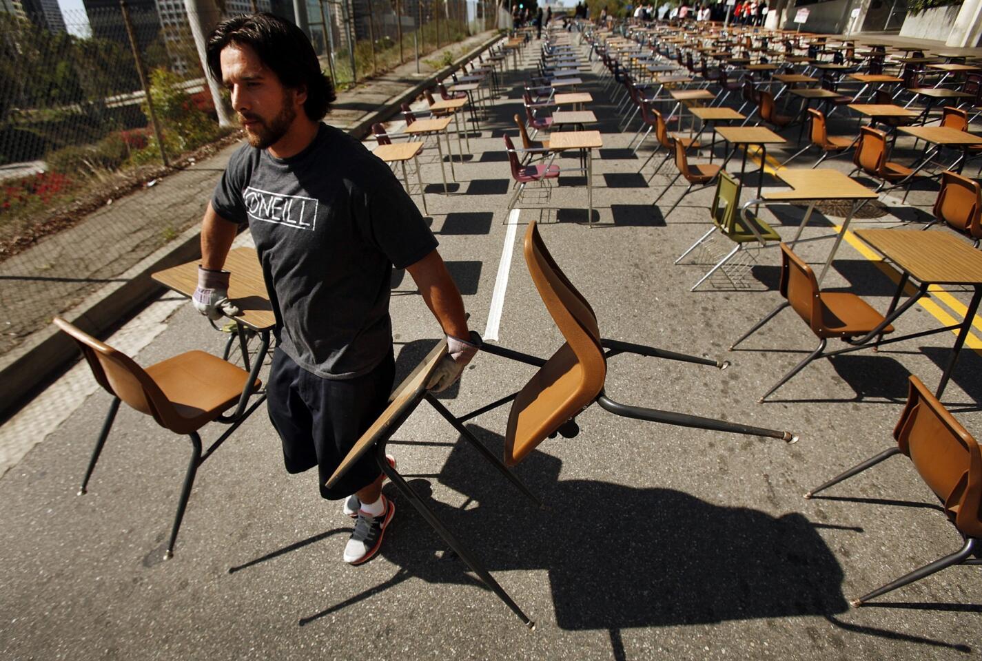 Ben Weischedel with the L.A. Rugby Club in support for United Way starts to load 375 school desks that were blocking Beaudry Avenue in front of L.A. Unified headquarters Tuesday. The 375 desks represent the number of students who drop out of school every week of a school year.