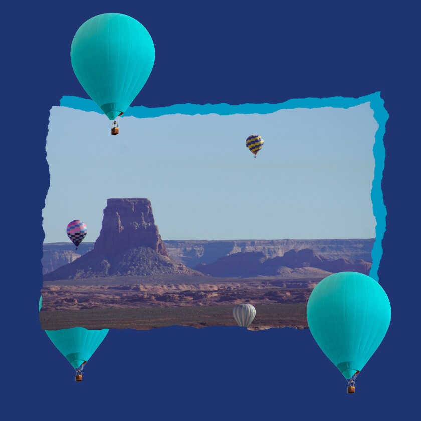 Hot air balloons rise above a chimney-shaped rock formation.