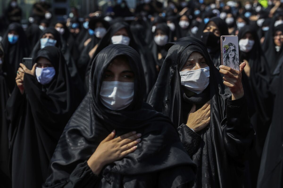 People wearing protective face masks to help prevent spread of the coronavirus mourn during an annual ceremony commemorating Ashoura, the anniversary of the 7th century death of Imam Hussein, a grandson of Prophet Muhammad, and one of Shiite Islam's most beloved saints, who was killed in a battle in Karbala in present-day Iraq, at the Saleh shrine in northern Tehran, Iran, Sunday, Aug. 30, 2020. Authorities allowed limited mourning rituals, urged social distancing and made wearing masks mandatory. (AP Photo/Ebrahim Noroozi)