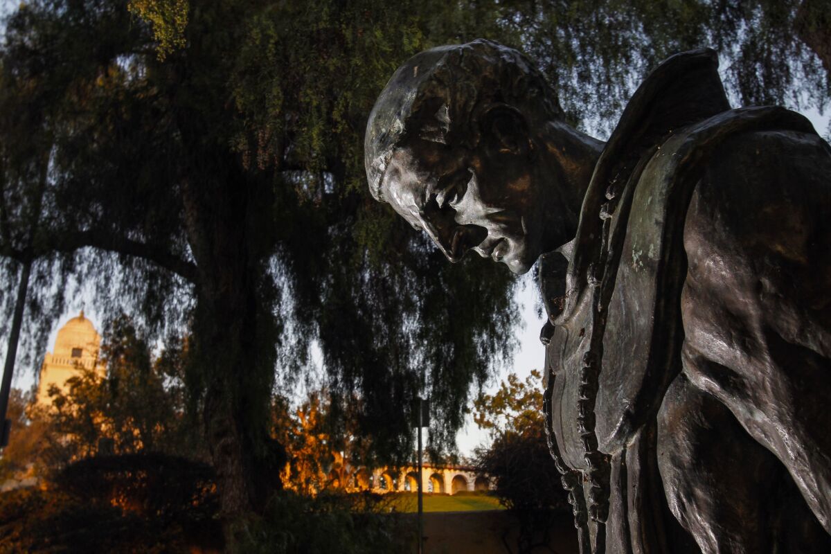 A statue titled "The Padre" is shown with the Junipero Serra Museum in the background at Presidio Park in San Diego.