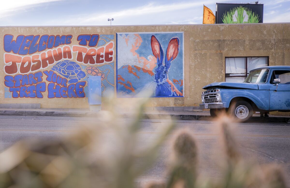The side of a building has artwork of a jackrabbit and the words "Welcome to Joshua Tree. Start your trip here."