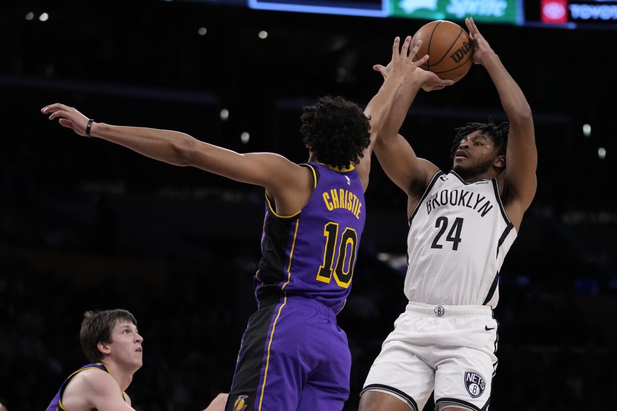 Lakers guard Max Christie tries to block a shot by Brooklyn Nets guard Cam Thomas.