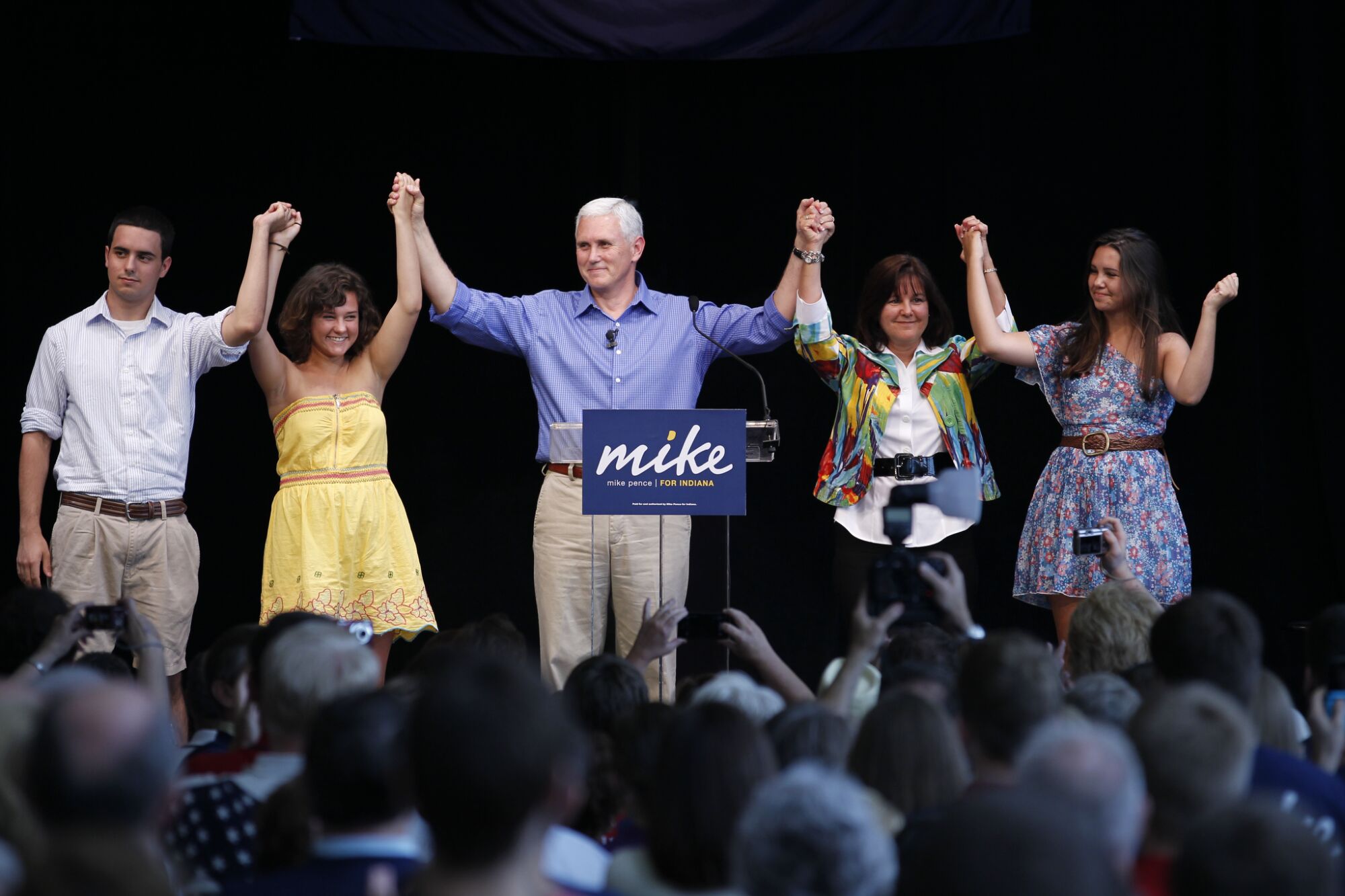 Mike Pence, wife Karen and their three children hold one another's hands high onstage as he campaigns for Indiana governor. 