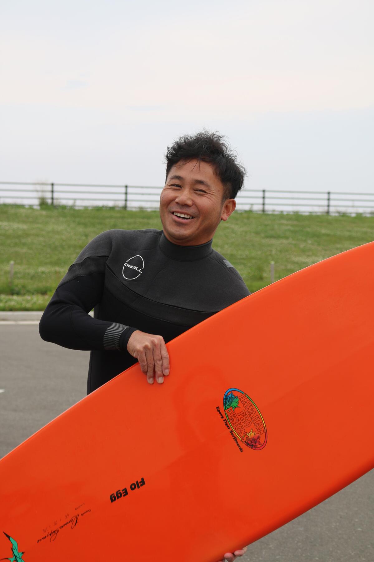 A smiling surfer holds his board.