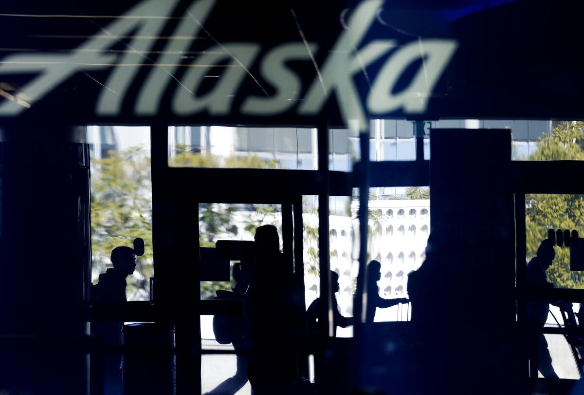 Travelers pass by Terminal 6 for Alaska Airlines at LAX.