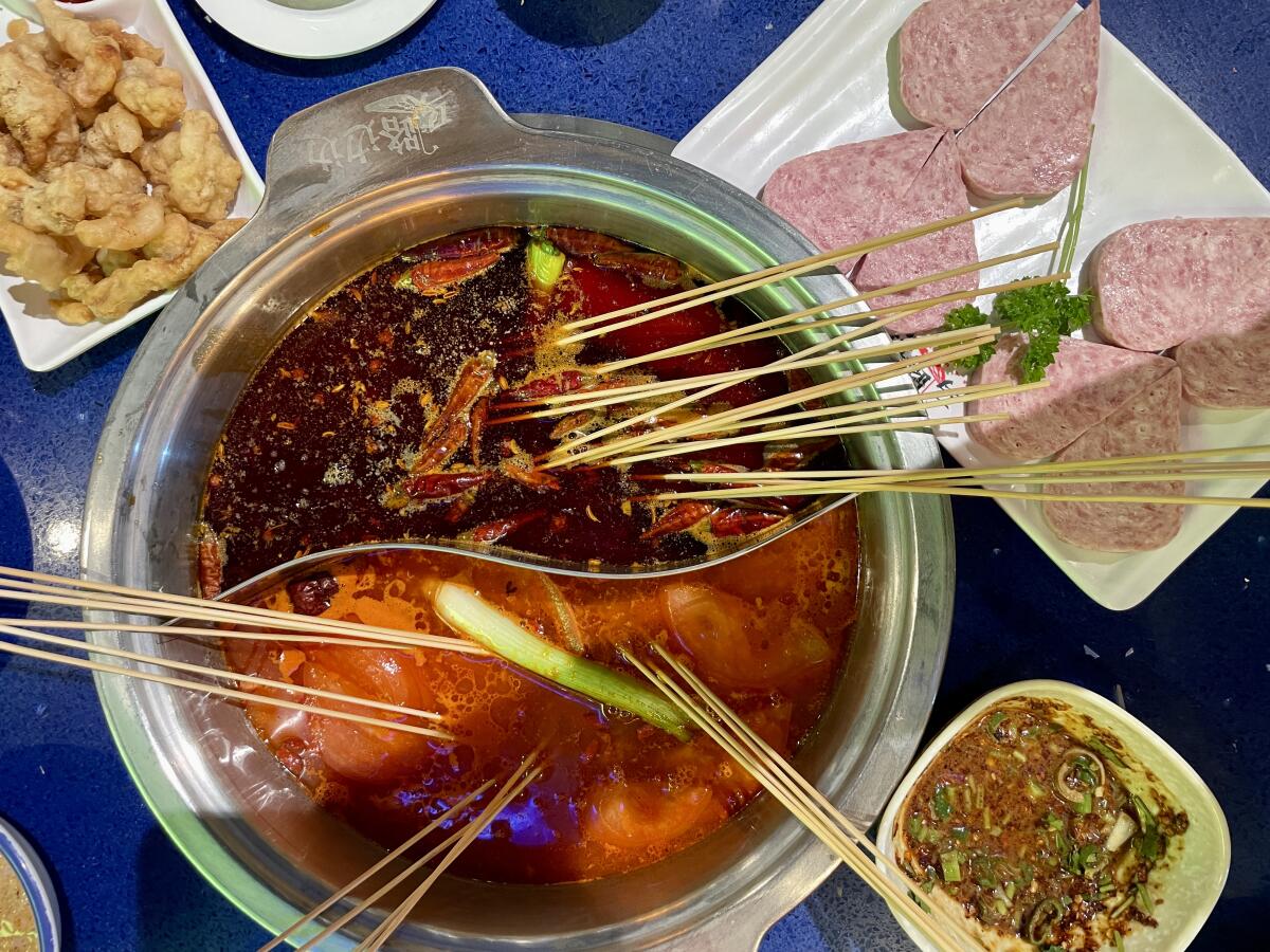 Hot pot with skewers of meat and shrimp alongside a plate of heart-shaped house-made Spam from Ma Lu Bian Bian in Tustin.