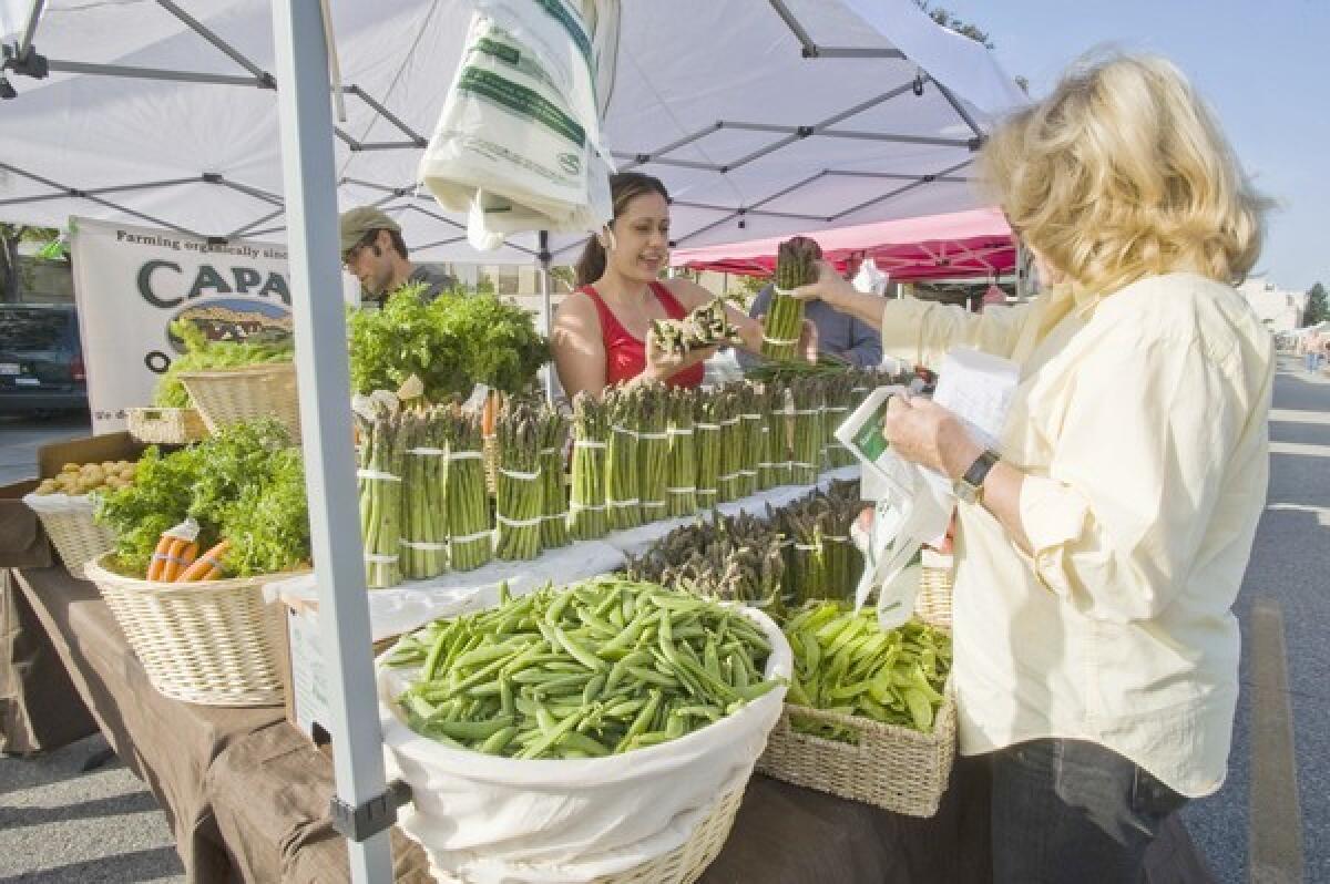 Aliya Hashemi sells asparagus to a customer at the Capay Organic farm stand at the Beverly Hills farmers market.