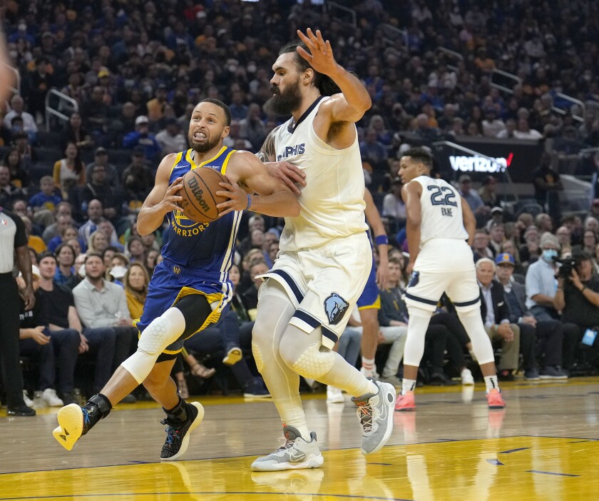 Stephen Curry, de los Warriors de Golden State, entra a canasta ante Steven Adams, de los Grizzlies de Memphis en la primera mitad del sexto juego de la serie de semifinales de la Conferencia Oeste, en San Francisco, el 13 de mayo de 2022. (AP Foto/Tony Avelar)