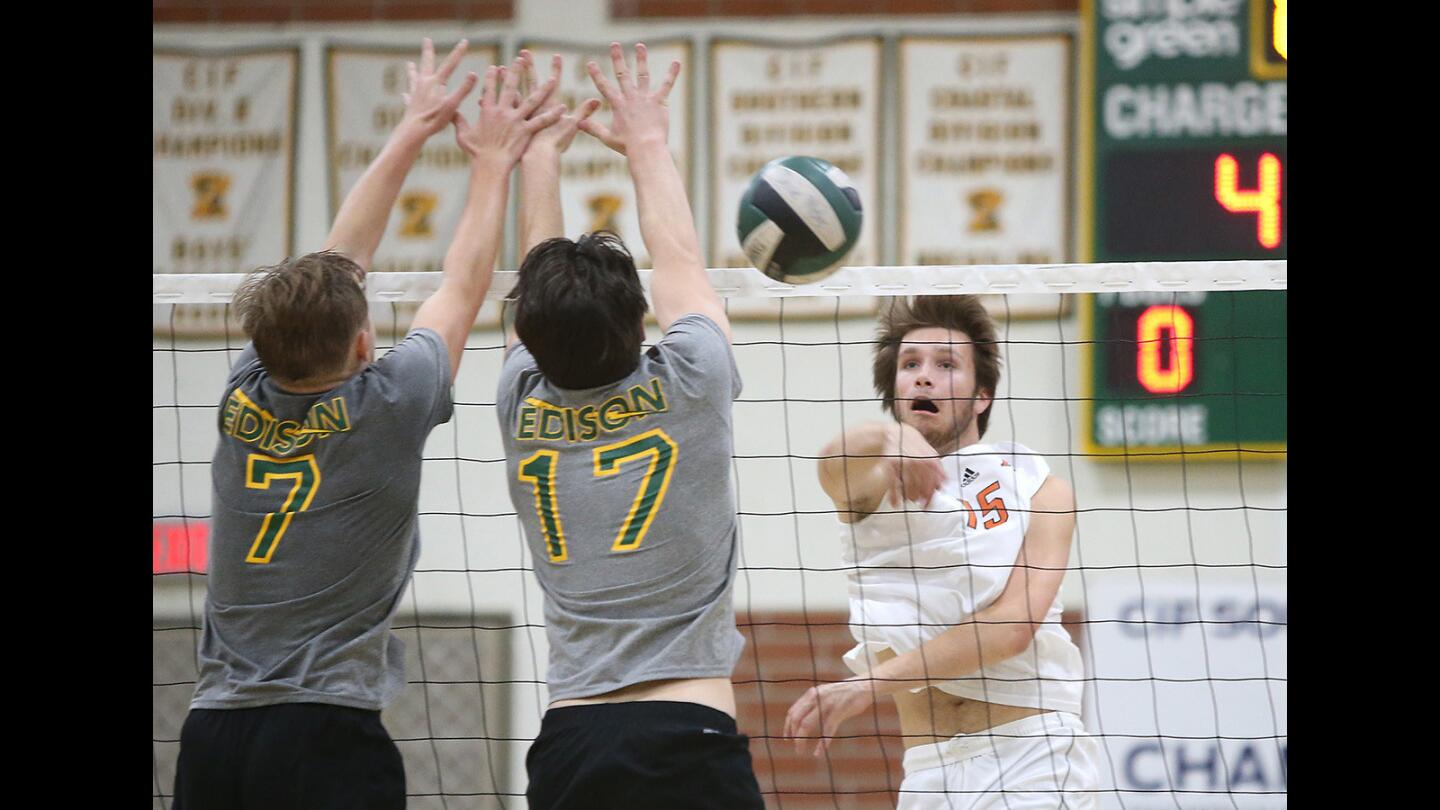 Huntington Beach's Ryan Bevington hits past Edison blockers James Carpenter and Trevor McCay, from left, during the Orange County Championships volleyball tournament at Edison High on Friday.