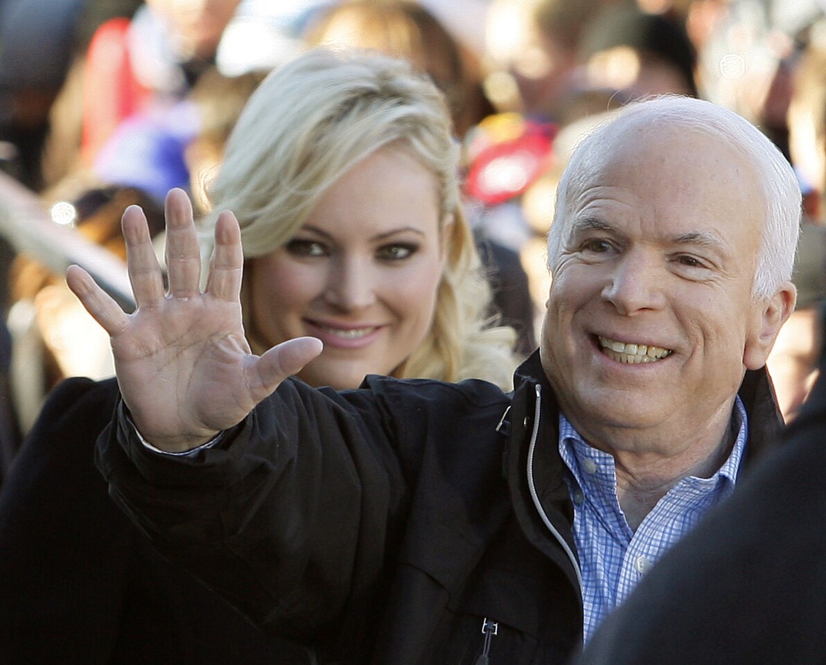 As a presidential candidate, John McCain waves to supporters in 2008 on the way into a campaign rally in Defiance, Ohio, accompanied by his daughter Meghan.