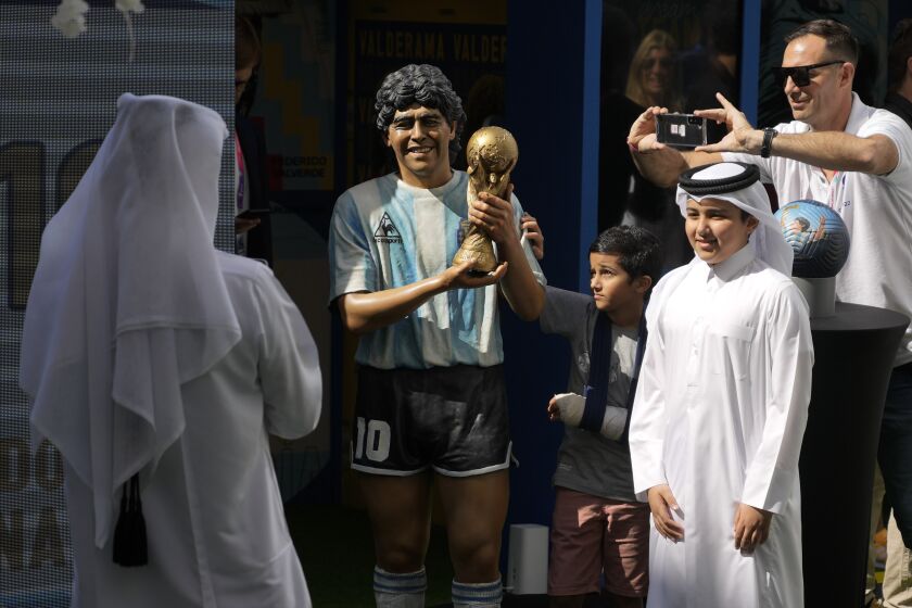 Un grupo de niños posan junto a una estatua de Diego Maradona durante una conmemoración en su honor en Doha, Qatar, el 25 de noviembre de 2022. (AP Foto/Jorge Saenz)