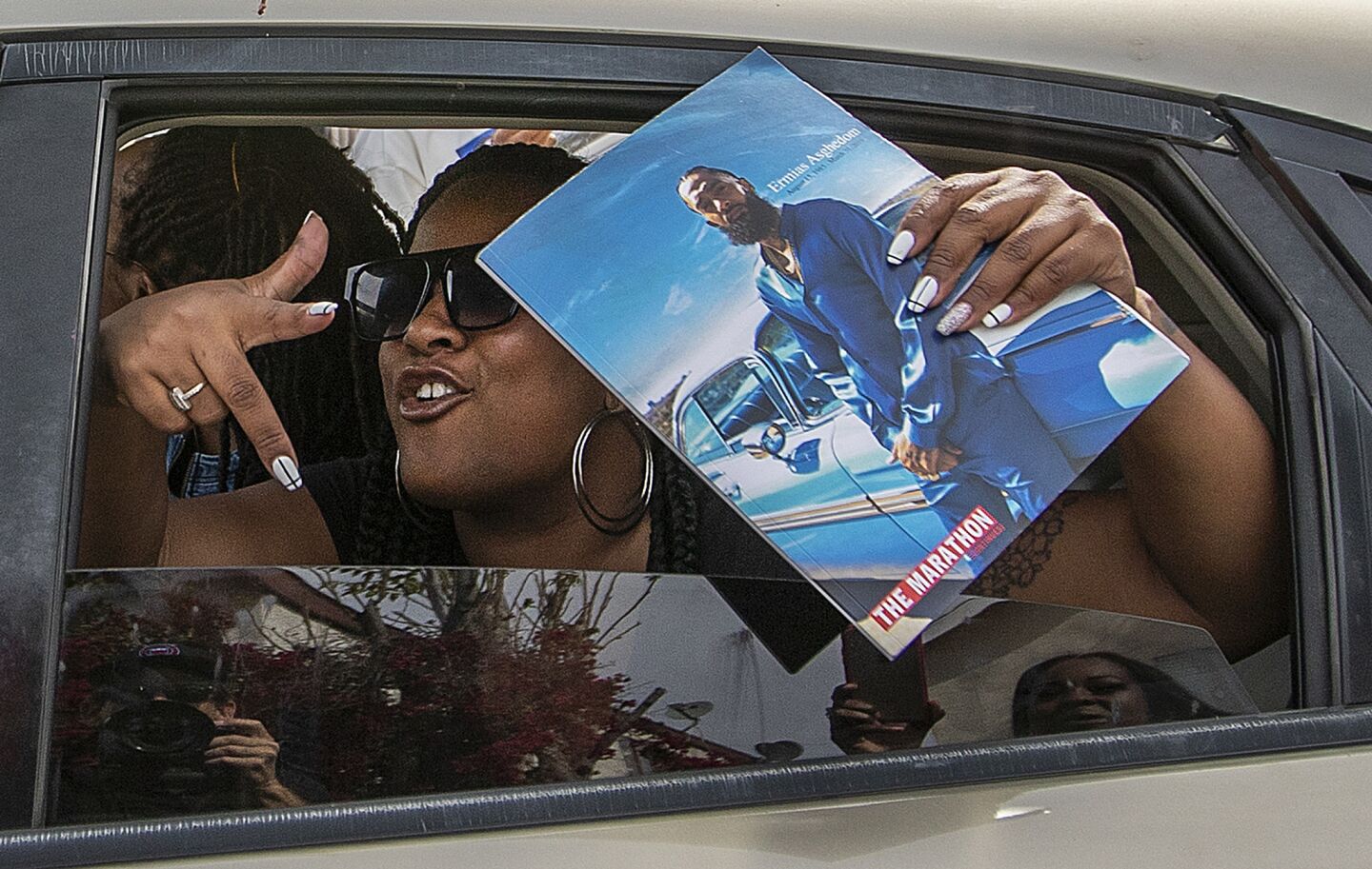 A woman holds a Nipsey Hussle memorial program in Watts.