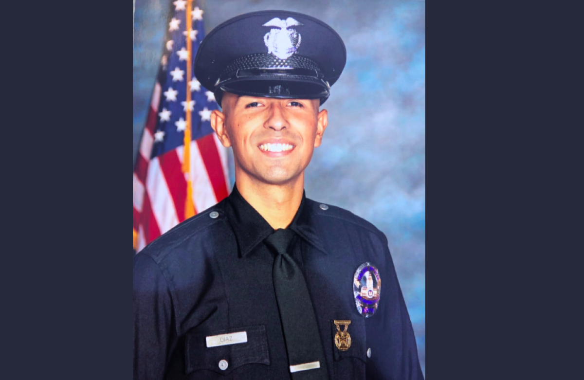 LAPD Officer Juan Jose Diaz in uniform with an American flag behind him.