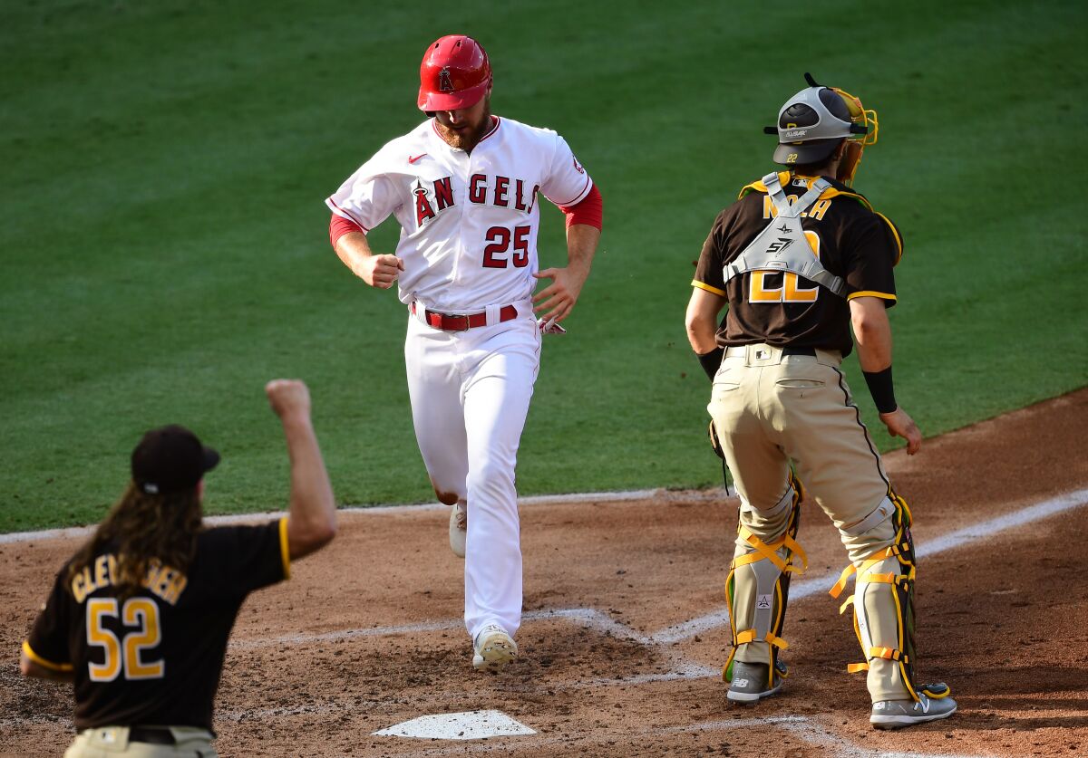 Angels' Jared Walsh scores in third inning Thursday at Angel Stadium as catcher Austin Nola and pitcher Mike Clevinger watch.