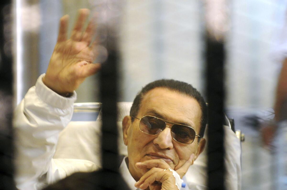 In this April 13 file photo, former Egyptian President Hosni Mubarak waves to his supporters from behind bars as he attends a court hearing in Cairo.
