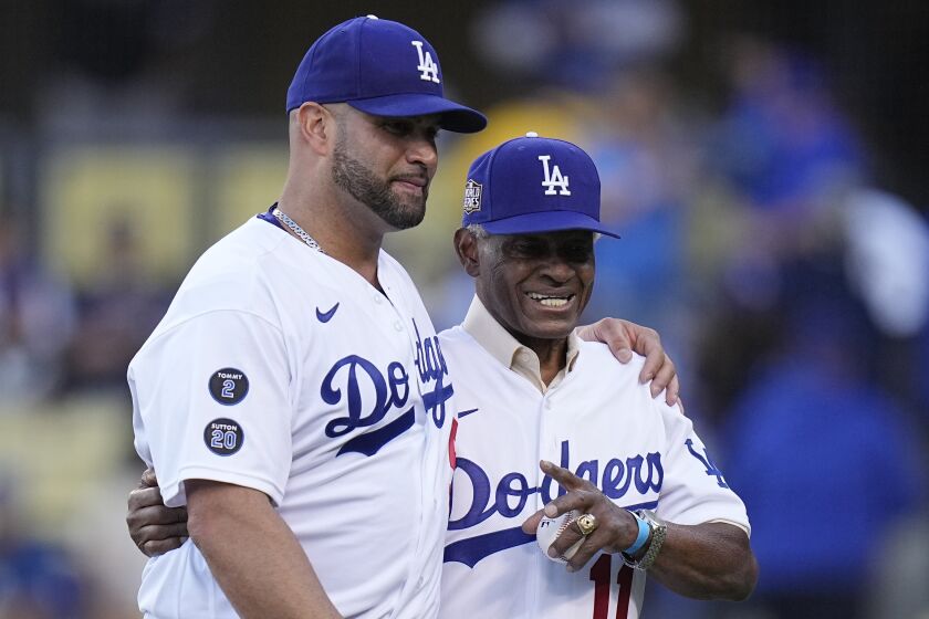 Los Angeles Dodgers' Albert Pujols walks with former Los Angeles Dodgers player Manny Mota.