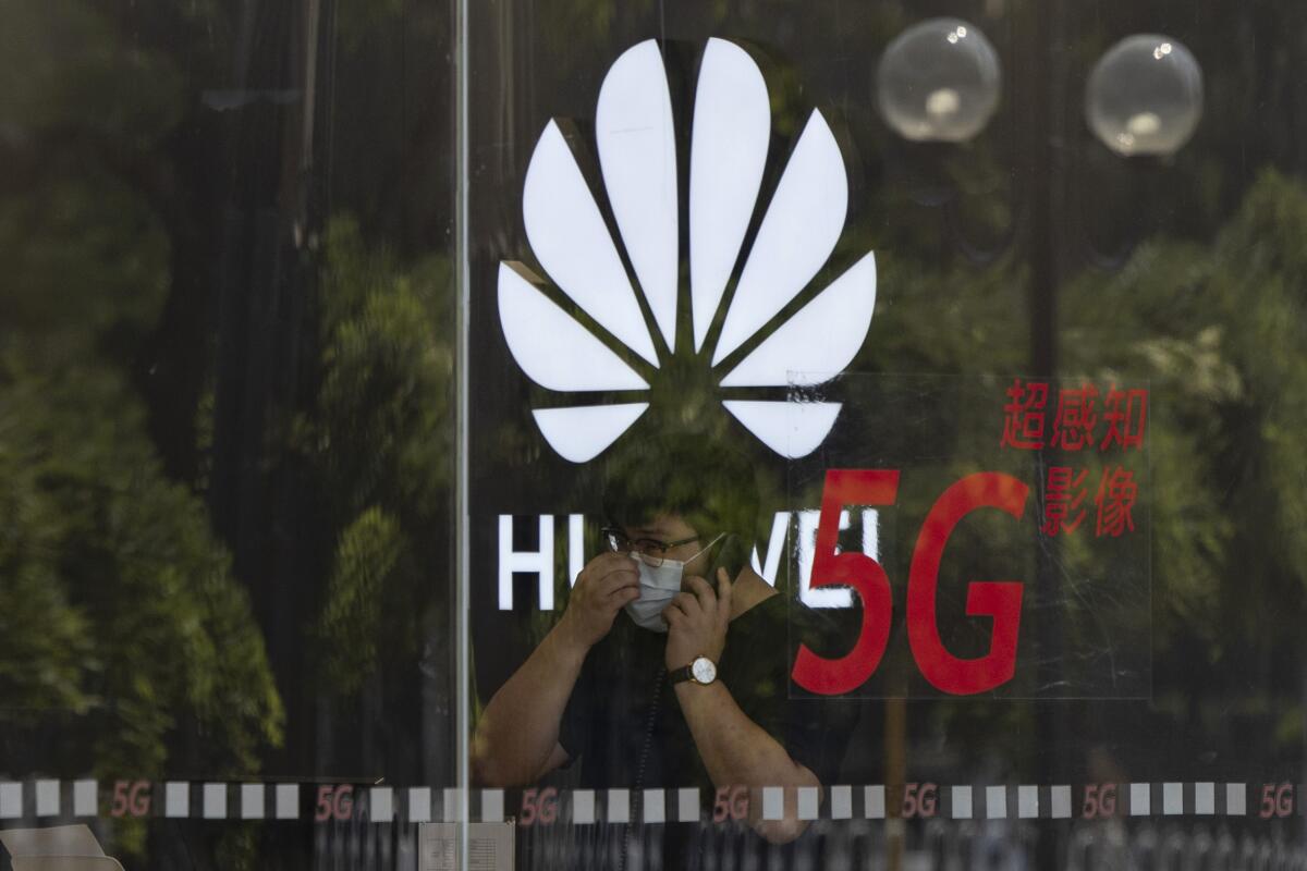 A worker speaks on the phone near the Huawei logo in a store