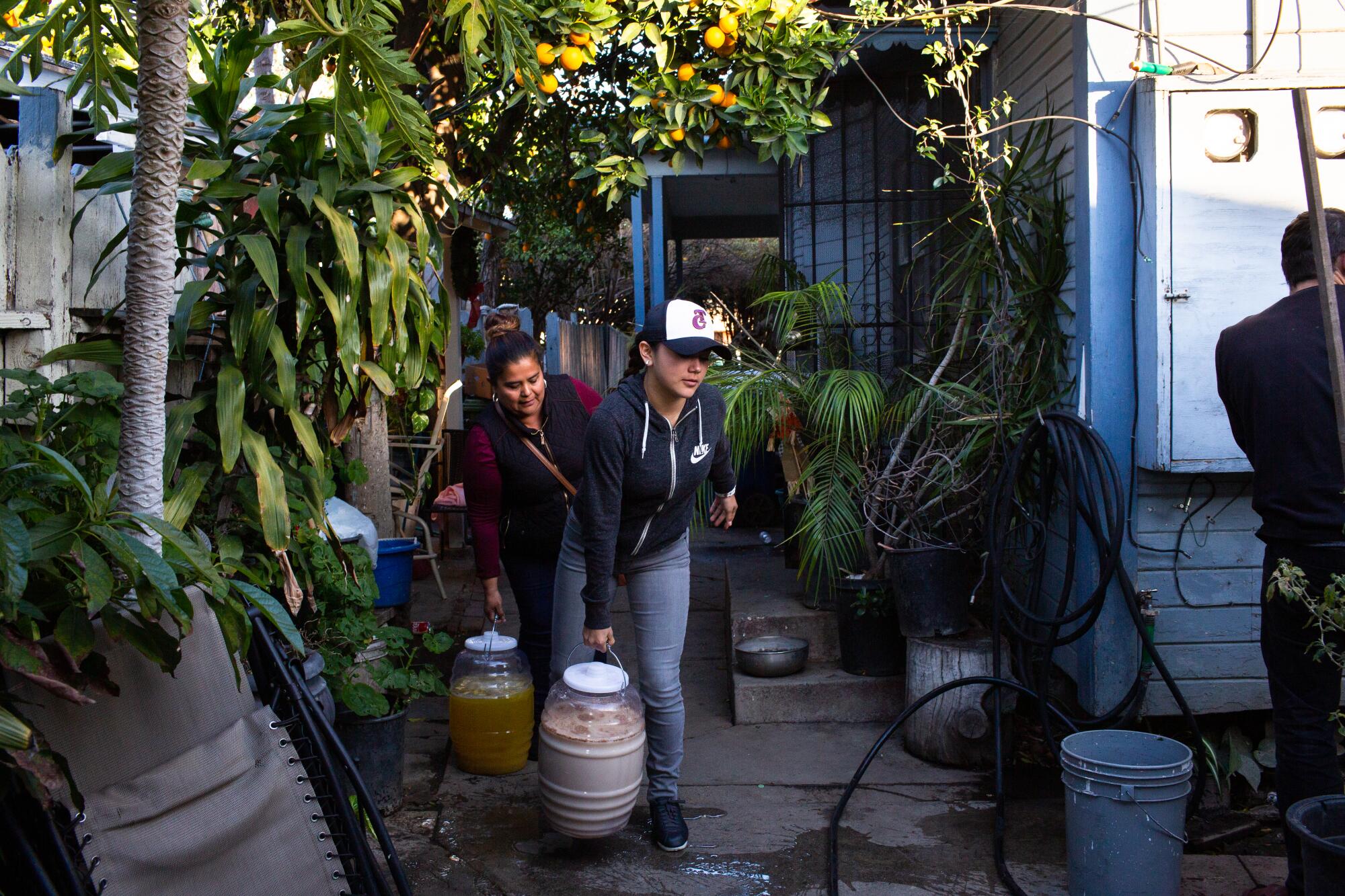 Elizabeth Meza, left, and Dalia Hurtado carry aguas to Elizabeth's pickup truck before a catering job.