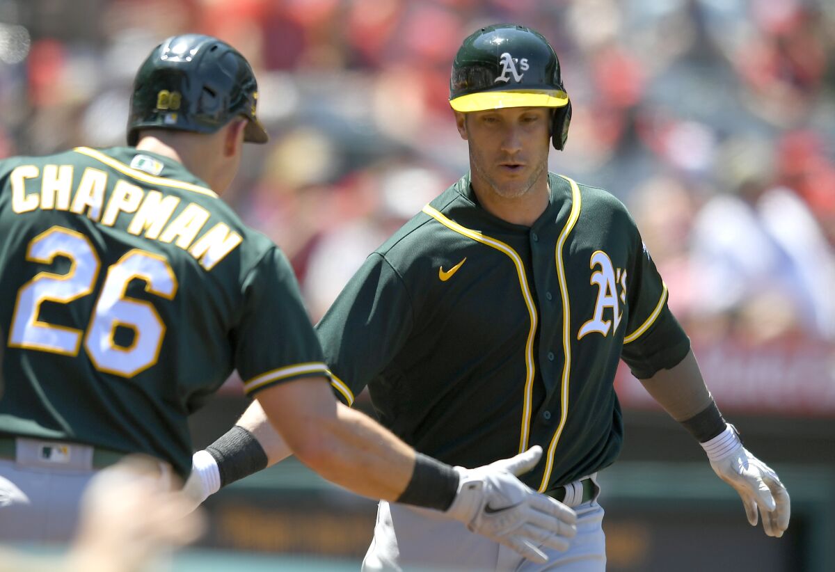 Oakland Athletics' Matt Chapman, left, congratulates Yan Gomes on his two-run home run in the fourth inning while playing against the Los Angeles Angels in a baseball game Sunday, Aug. 1, 2021, in Anaheim, Calif. (AP Photo/John McCoy)