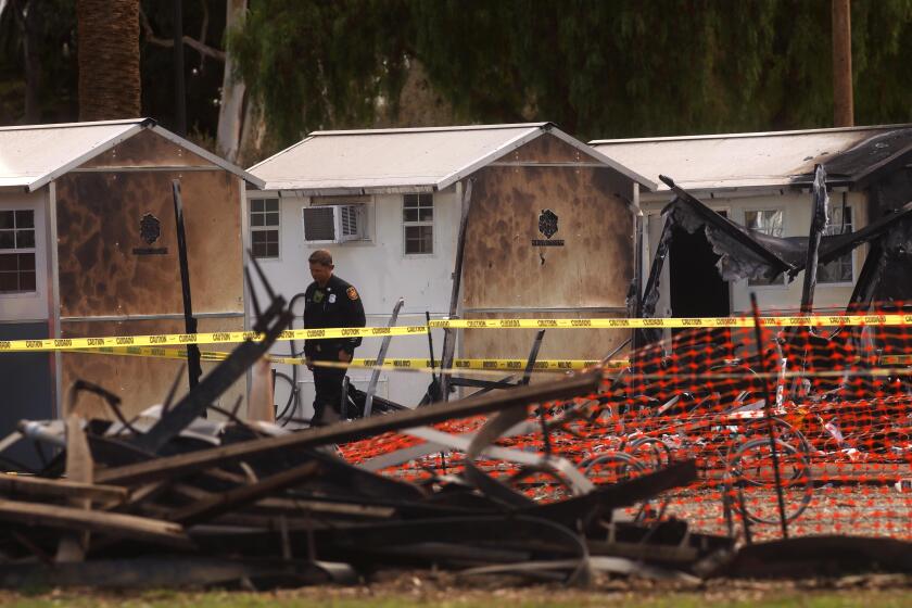 WEST LOS ANGELES, CA - SEPTEMBER 9, 2022 - - A fire official walks past some of the tiny home shelters that were damaged or destroyed in a fire Friday morning on the West Los Angeles Veterans Affairs campus on September 9, 2022. There were no immediate signs of foul play according to fire officials but the cause of the fire remains under investigation. The tiny homes village was erected after the VA cleared a makeshift encampment on San Vicente Boulevard in November. The West LA encampment, known as Veterans Row, was cleared last year and many of the veterans were moved into the tiny home shelters. (Genaro Molina / Los Angeles Times)
