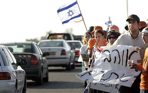Supporters of Gush Katif settlers line the highway leading out of the Gaza Strip settlements Wednesday, holding signs and waving flags for the long line of settlers streaming out on the first day of forced evacuations.