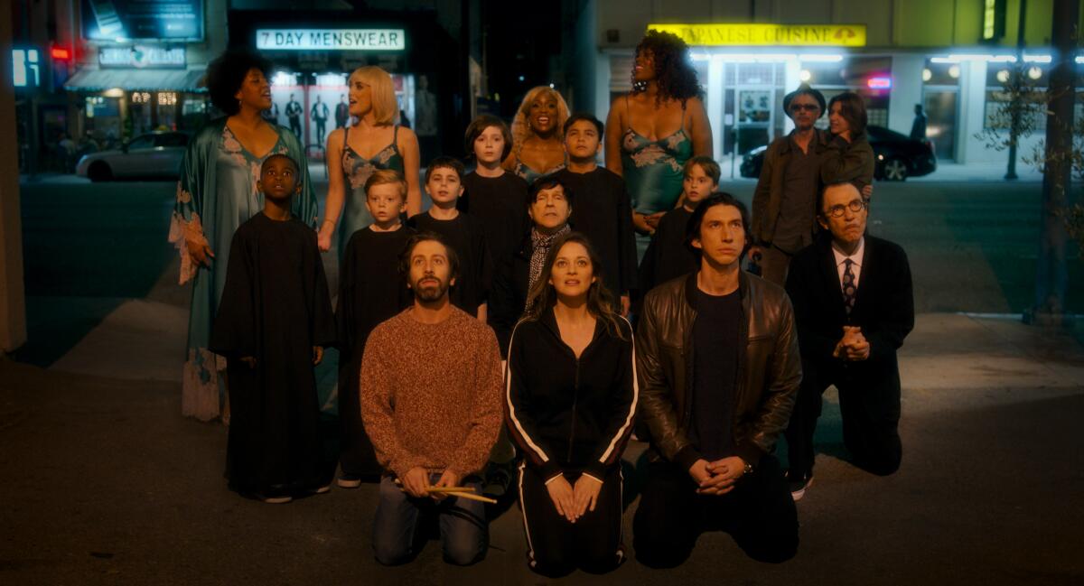 Three rows of people stand and one row kneels in front of storefronts