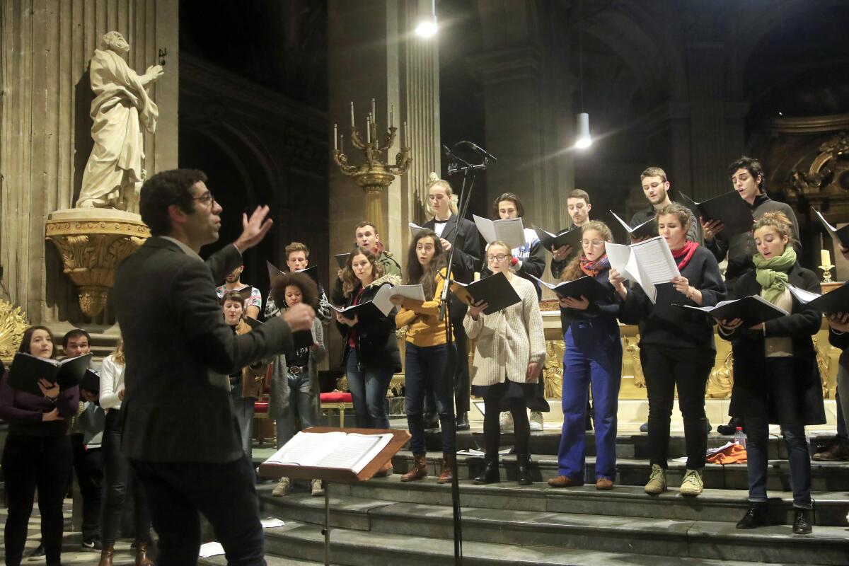 Henri Chalet directs the Notre Dame Cathedral's choir during a rehearsal at the St. Sulpice church in Paris on Monday, as the choir continues in other venues.