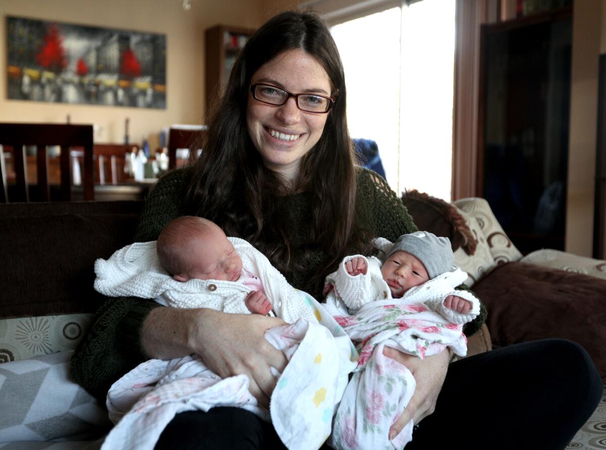 New mom and identical twin Jenny Tarzian holds newborn identical twins Celia Jill and Naomi Carol Friday at her Pasadena home. Tarzian's own twin, Rae Wannier, was with her during the Feb. 6 delivery.