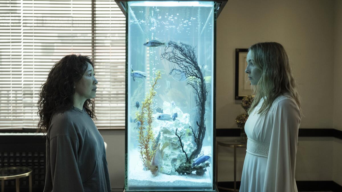 Two women face each other with a fish tank between them.