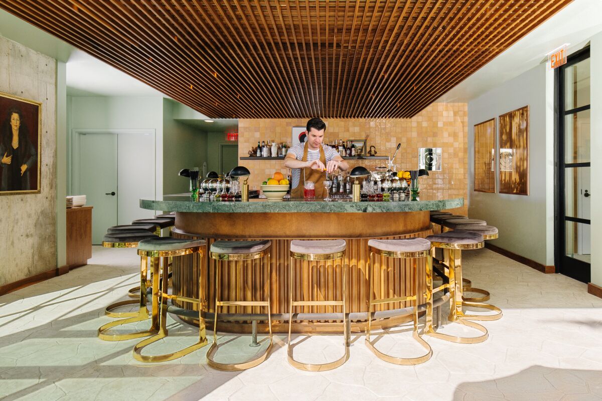 A bartender makes a drink behind a bar.