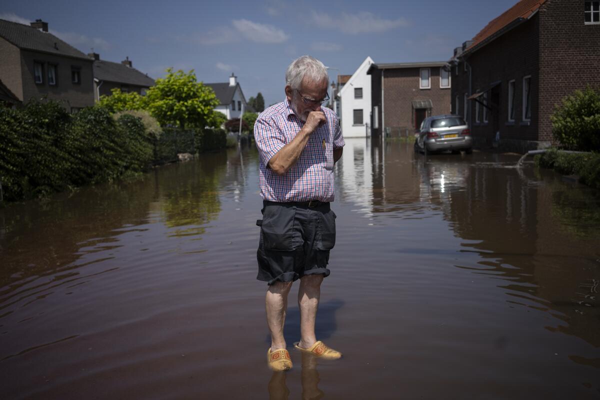 Wiel de Bie stands in water in the street outside his flooded home in the Netherlands on Saturday.