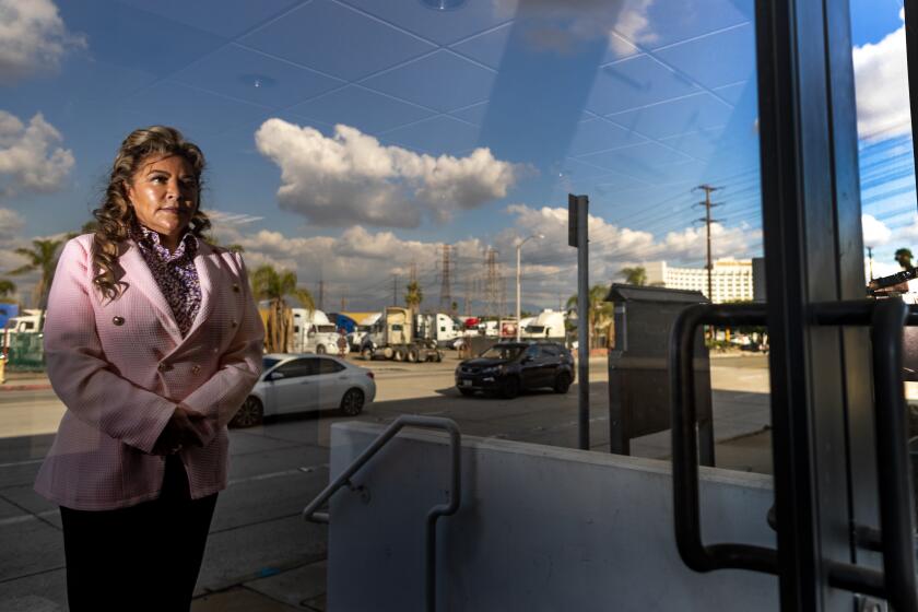 COMMERCE, CA - DECEMBER 7, 2022: Board member Leticia Vasquez is reflected in the front doors of the old Central Basin Municipal Water District building off Telegraph Road on December 7, 2022 in Commerce, California. Vasquez has vehemently criticized General Manager Alex Rojas, pointing out that he was charged in August with money laundering, soliciting a bribe and grand theft by embezzlement. She is demanding the board consider additional measures to safeguard its finances against potential fraud.(Gina Ferazzi / Los Angeles Times)