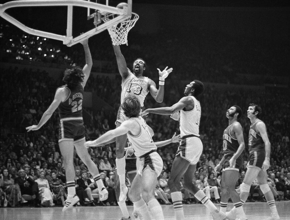 Wilt Chamberlain goes up to tap in a basket for the Lakers against the New York Knicks. Other players are surrounding him.