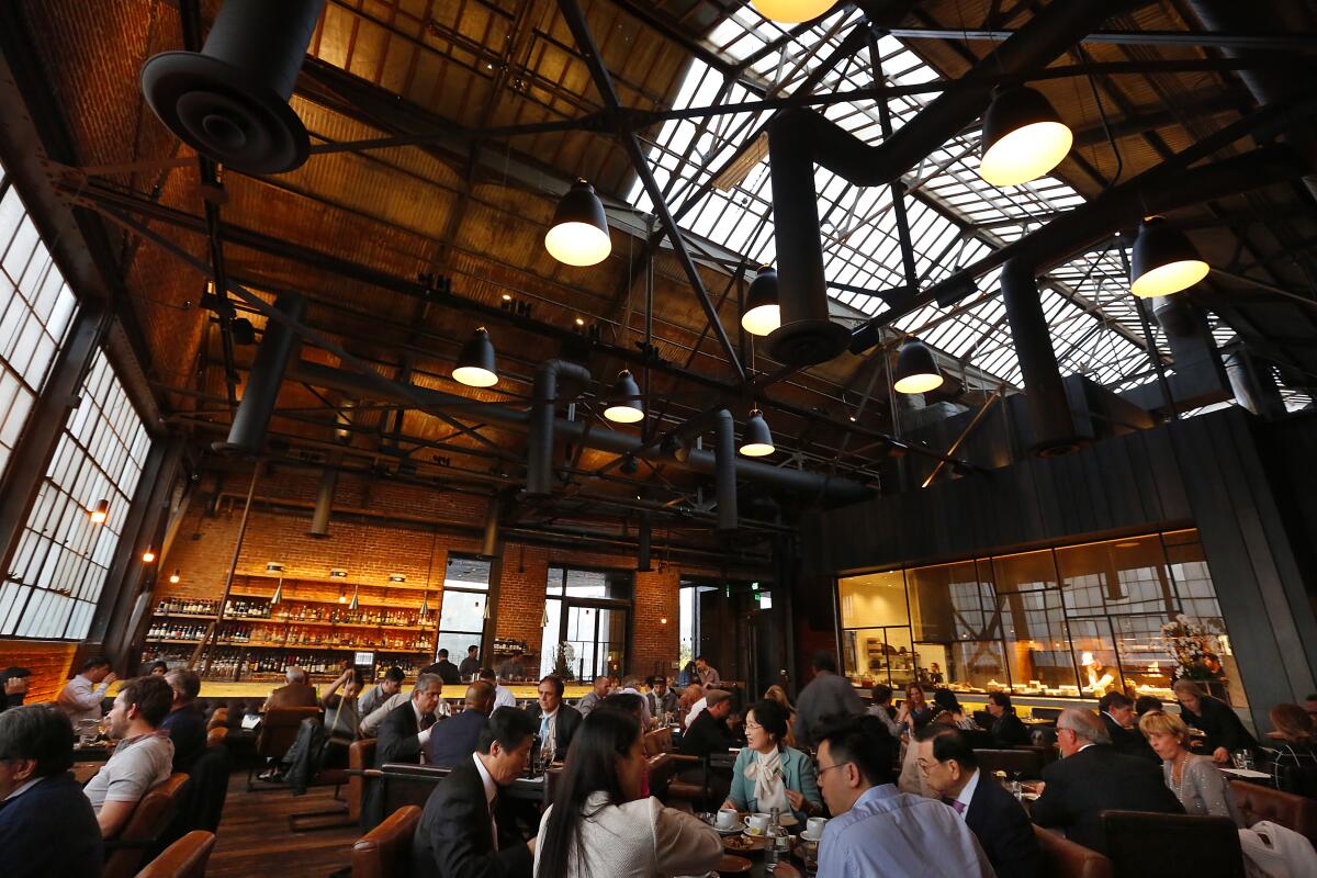 Customers dine in a restaurant with a high ceiling and skylights