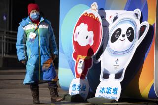 A woman wearing a face mask to protect against COVID-19 stands next to figures of the Winter Paralympic mascot Shuey Rhon Rhon left, and Winter Olympic mascot Bing Dwen Dwen on a pedestrian shopping street in Beijing, Saturday, Jan. 15, 2022. As the Beijing Winter Olympics loom, the Chinese capital is stepping measures to keep the coronavirus at bay including suspending most access to Tianjin, an adjacent major city which is dealing with an outbreak of the highly contagious omicron variant. These outbreaks are posing a test to its "zero-tolerance" COVID-19 policy and its ability to successfully host the Winter Olympics. (AP Photo/Mark Schiefelbein)
