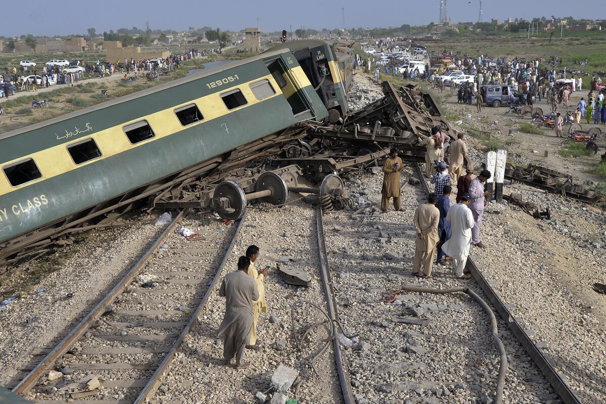 Local residents examine damaged cars of a derailed passenger train.