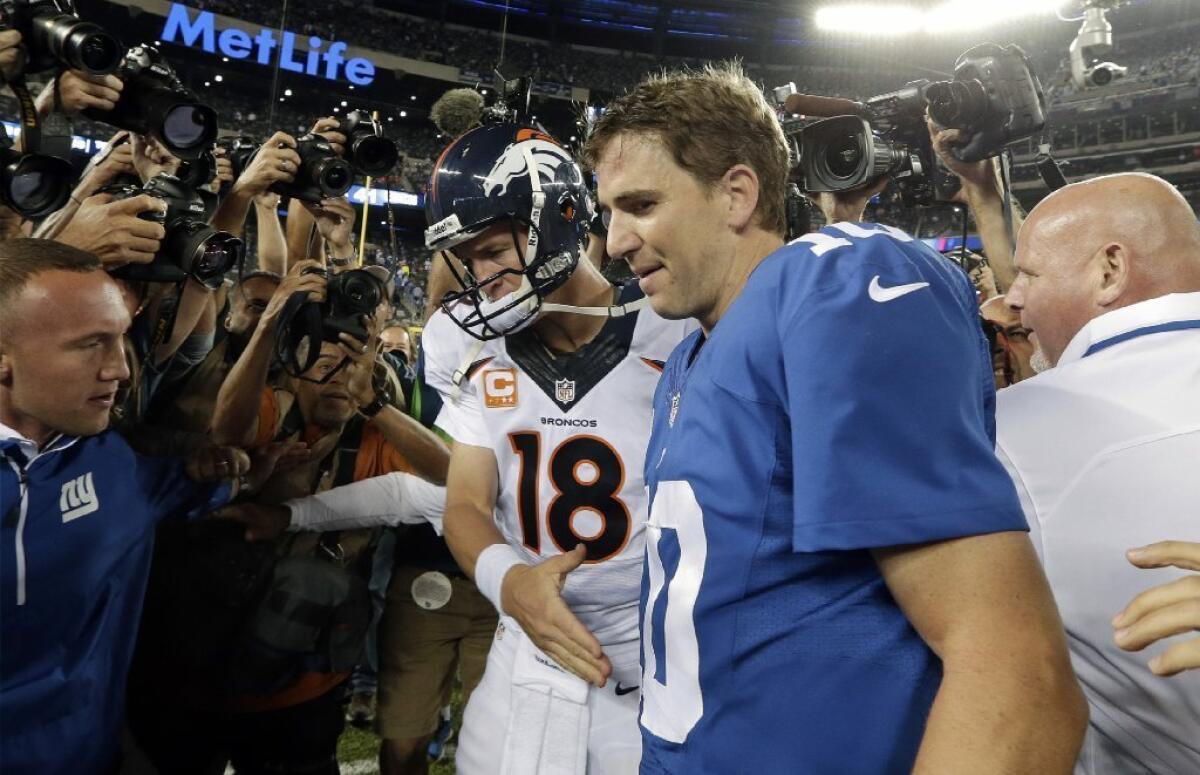 Peyton and Eli Manning walk off the field after a game in September.