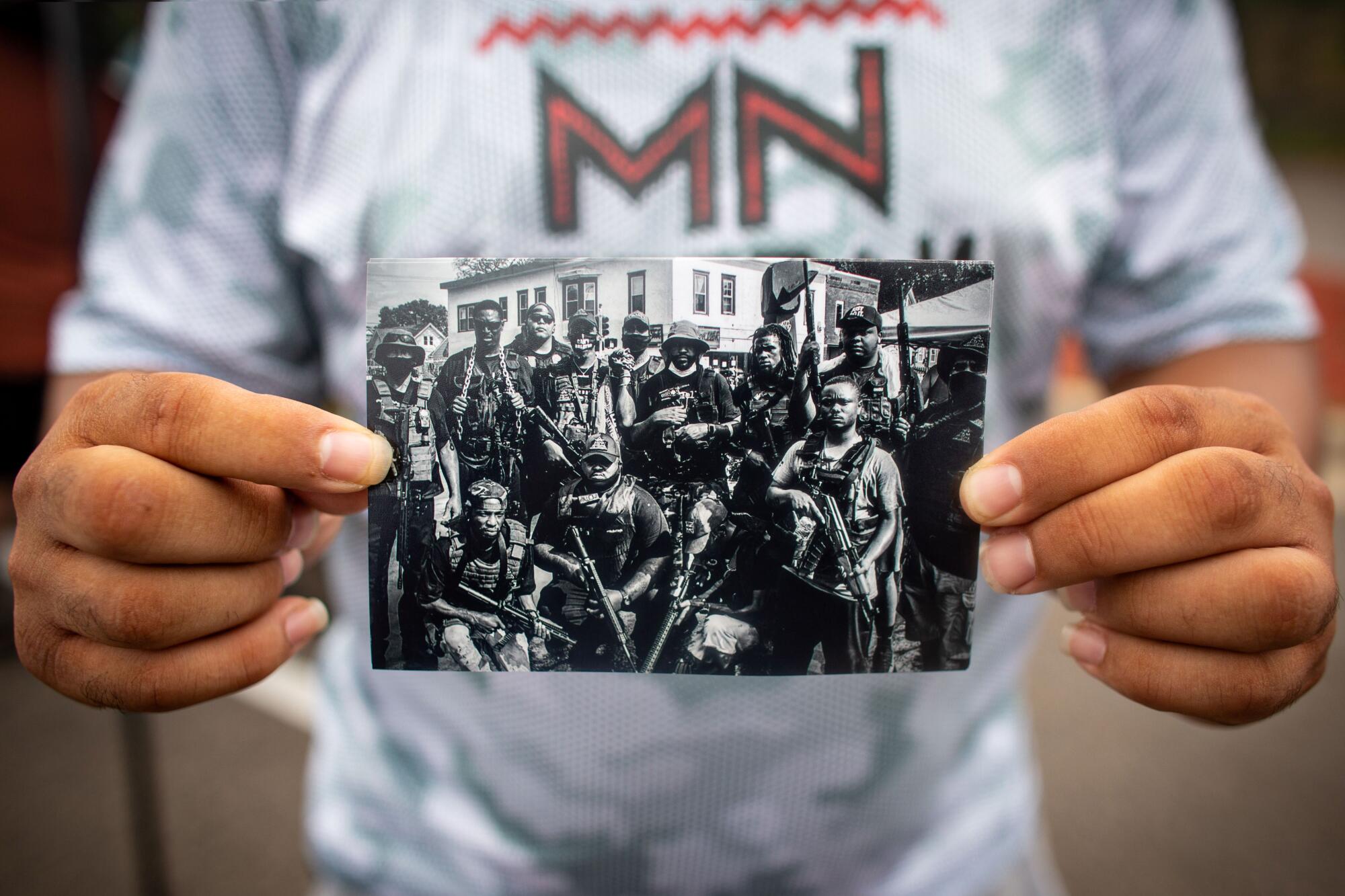 Romeal Taylor holds a photo of the Minnesota Freedom Fighters outside Cup Foods, where George Floyd died.